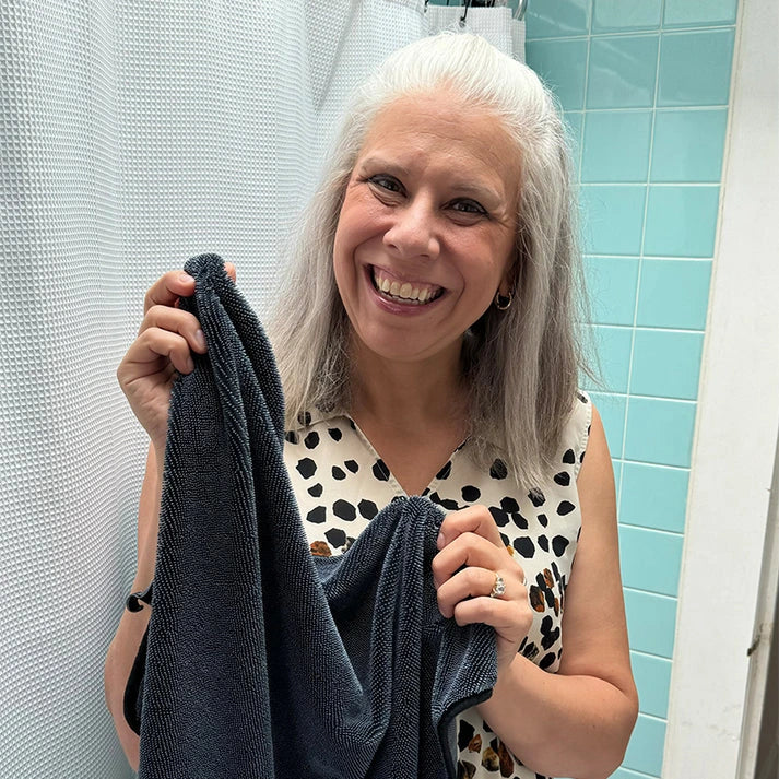 Woman holding a towel in a bathroom with light blue tiles.